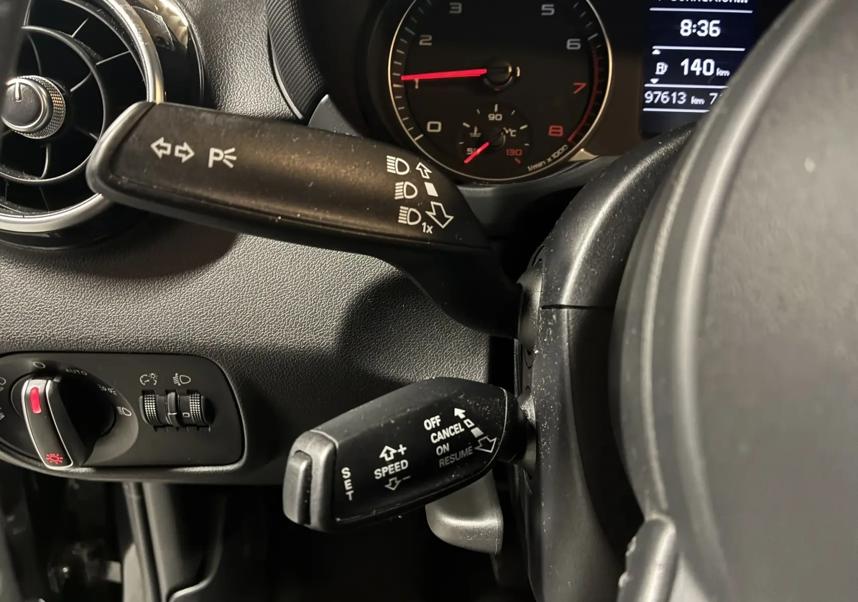 Gros plan sur la commande de clignotants et régulateur de vitesse dans l’habitacle gris-noir d’une Audi A1 2016.