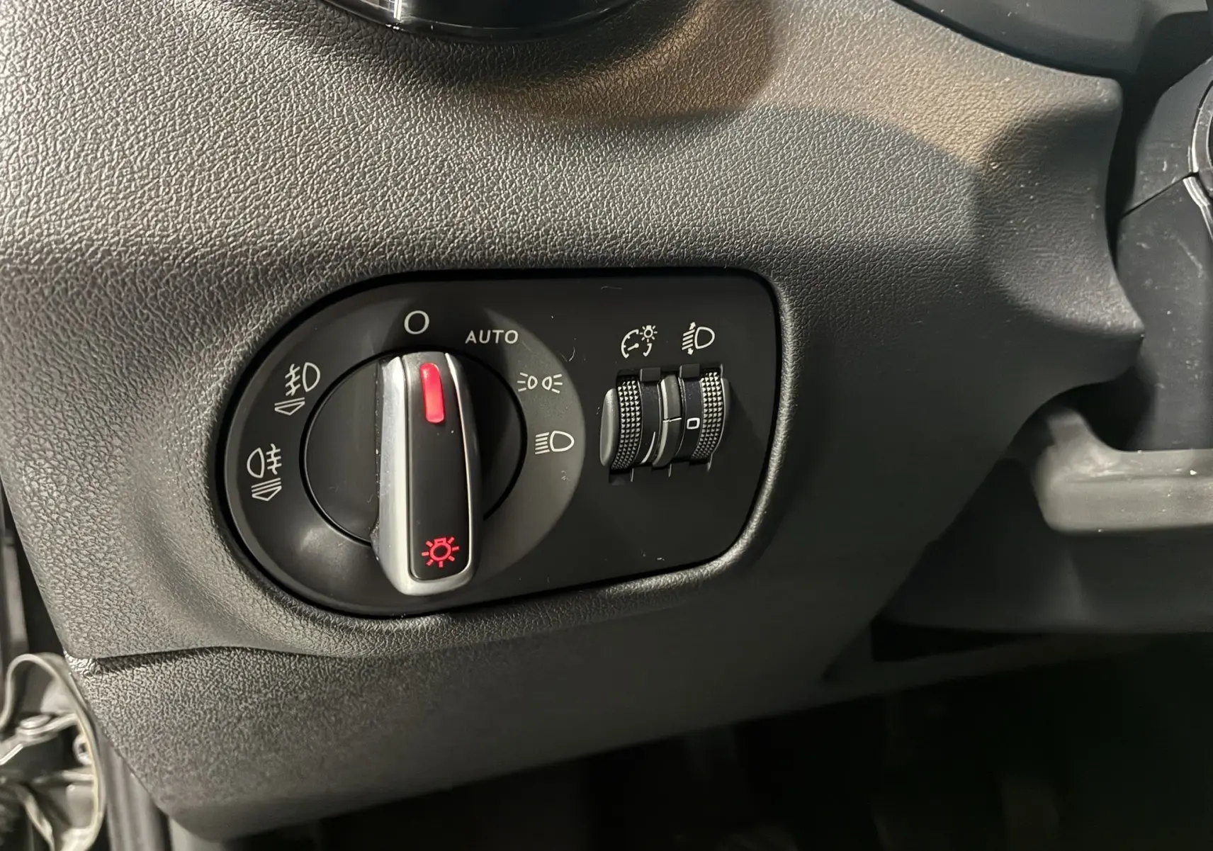 Gros plan sur le bouton de commande des phares et réglages d’éclairage intérieur noir dans l’Audi A1 2016 S-Line.