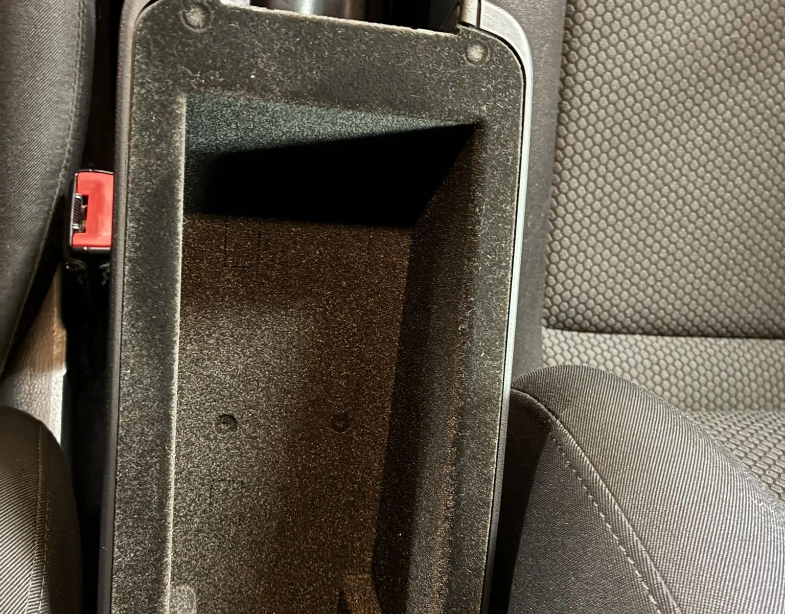 Vue plongeante sur le rangement central ouvert entre les sièges en tissu gris foncé de l'Audi A1 1.0 TFSI S-Line noire de 2016.