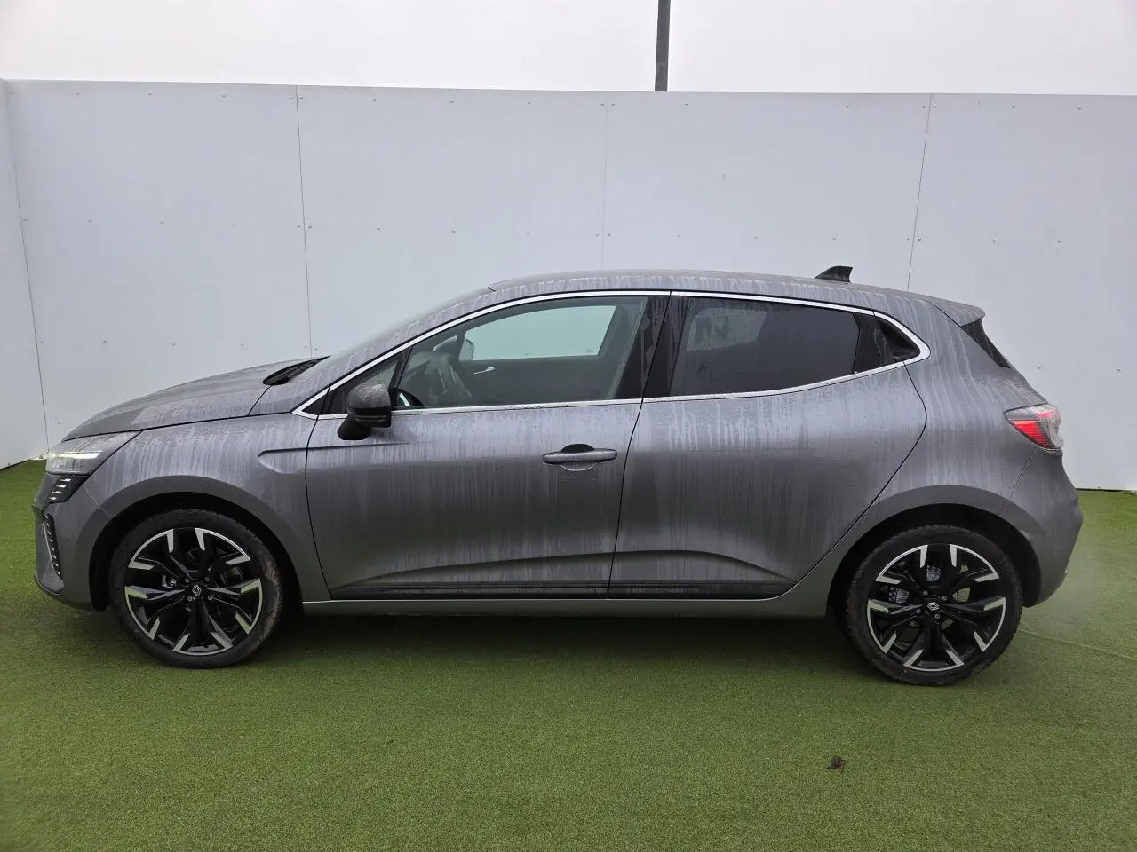 Profil côté gauche de la Renault Clio 2025 gris schiste métal avec jantes alliage noires et vitres surteintées.