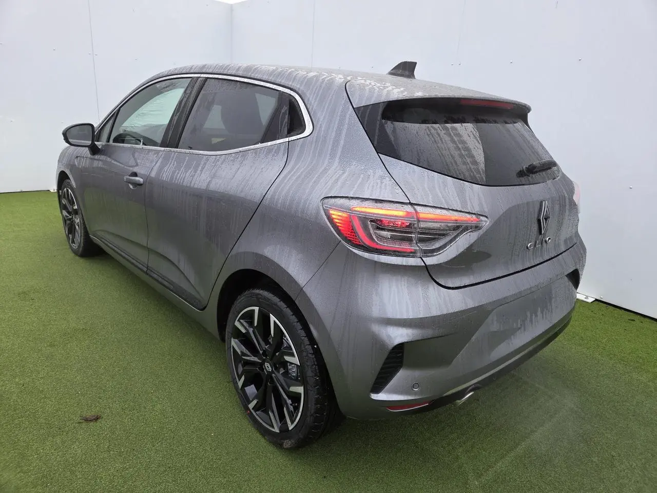 Vue 3/4 arrière droite d'une Renault Clio gris schiste métallisé avec jantes alliage noires et vitres surteintées.