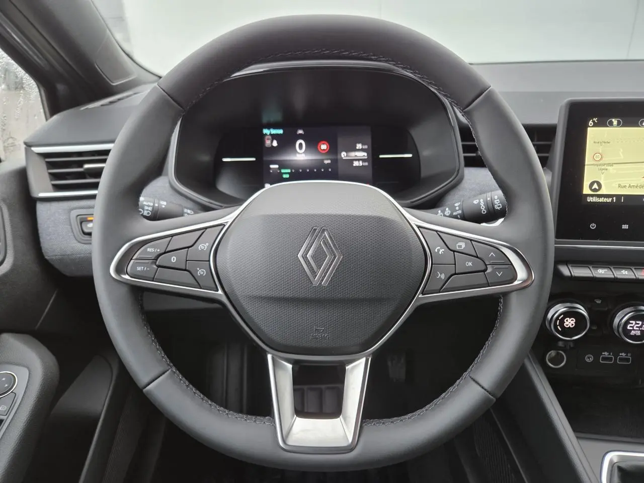 Vue rapprochée du volant multifonction noir et du tableau de bord numérique de la Renault Clio 2025.