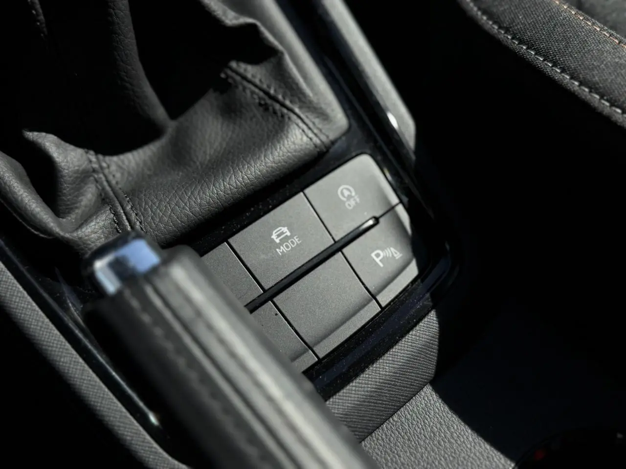 Gros plan sur les commandes noires près du levier de frein à main en cuir dans l'habitacle d'une Skoda Scala 2025.