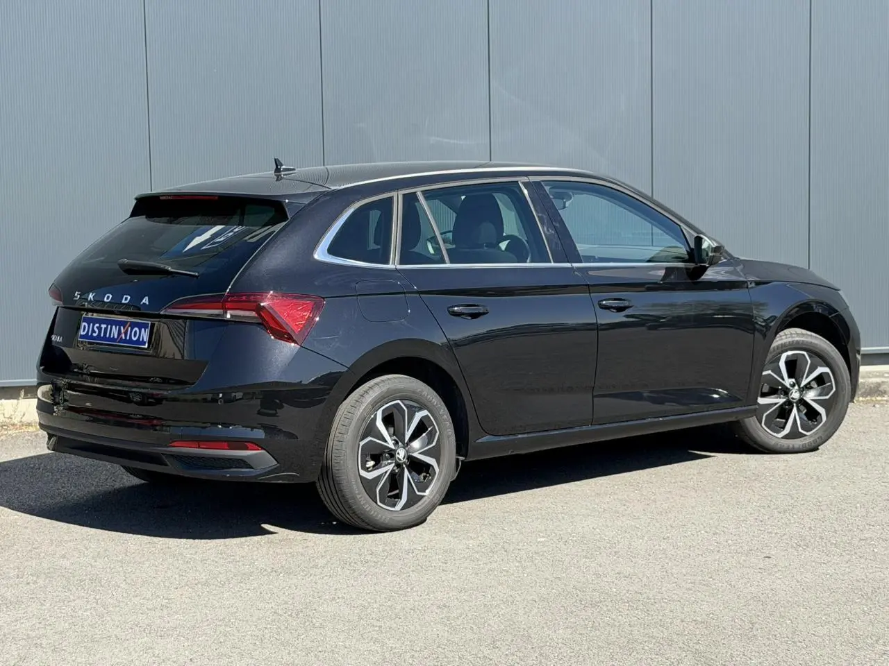 Vue 3/4 arrière droite d'une Skoda Scala noire Magic Perle avec jantes alliage et vitres surteintées.