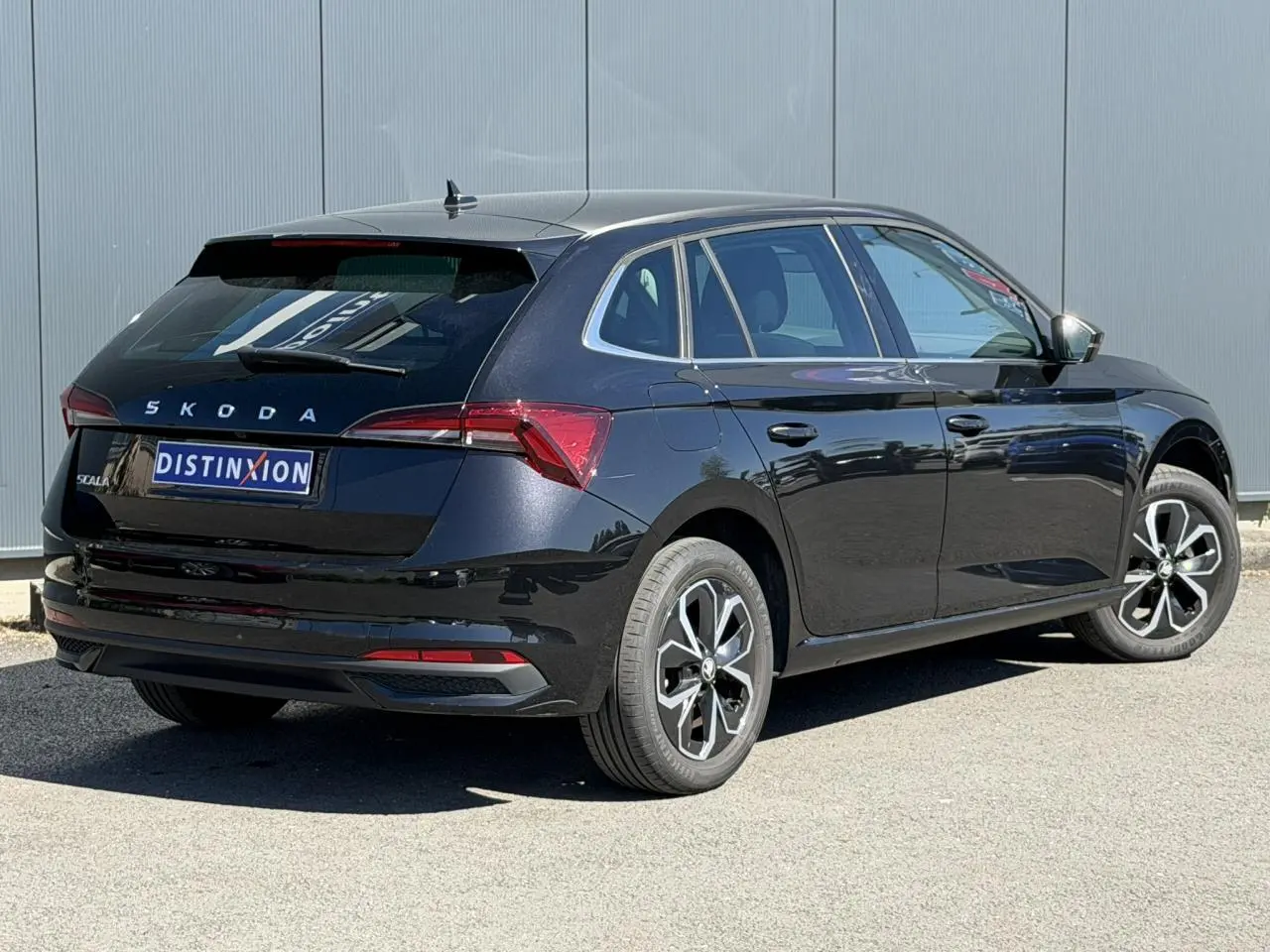 Vue 3/4 arrière droite d'une Skoda Scala noire Magic Perle avec jantes alliage et vitres surteintées.