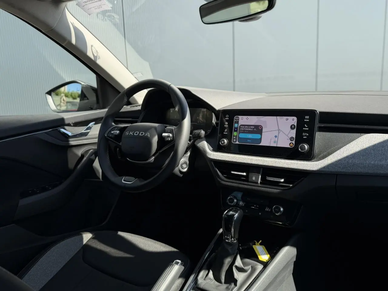 Intérieur de la Skoda Scala TSI 116 DSG7 vu côté conducteur, volant noir et écran tactile central allumé.