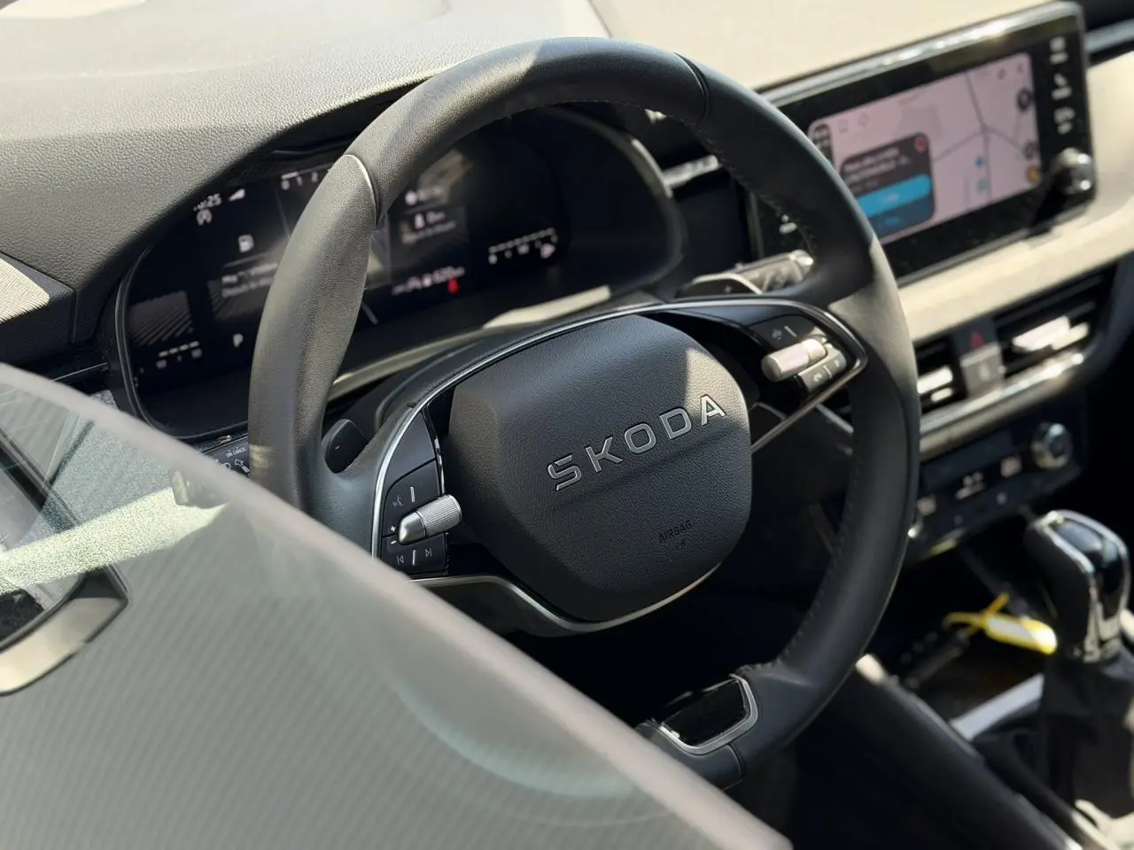 Vue rapprochée du volant noir multifonctions SKODA dans l’habitacle avec tableau de bord digital et écran tactile.