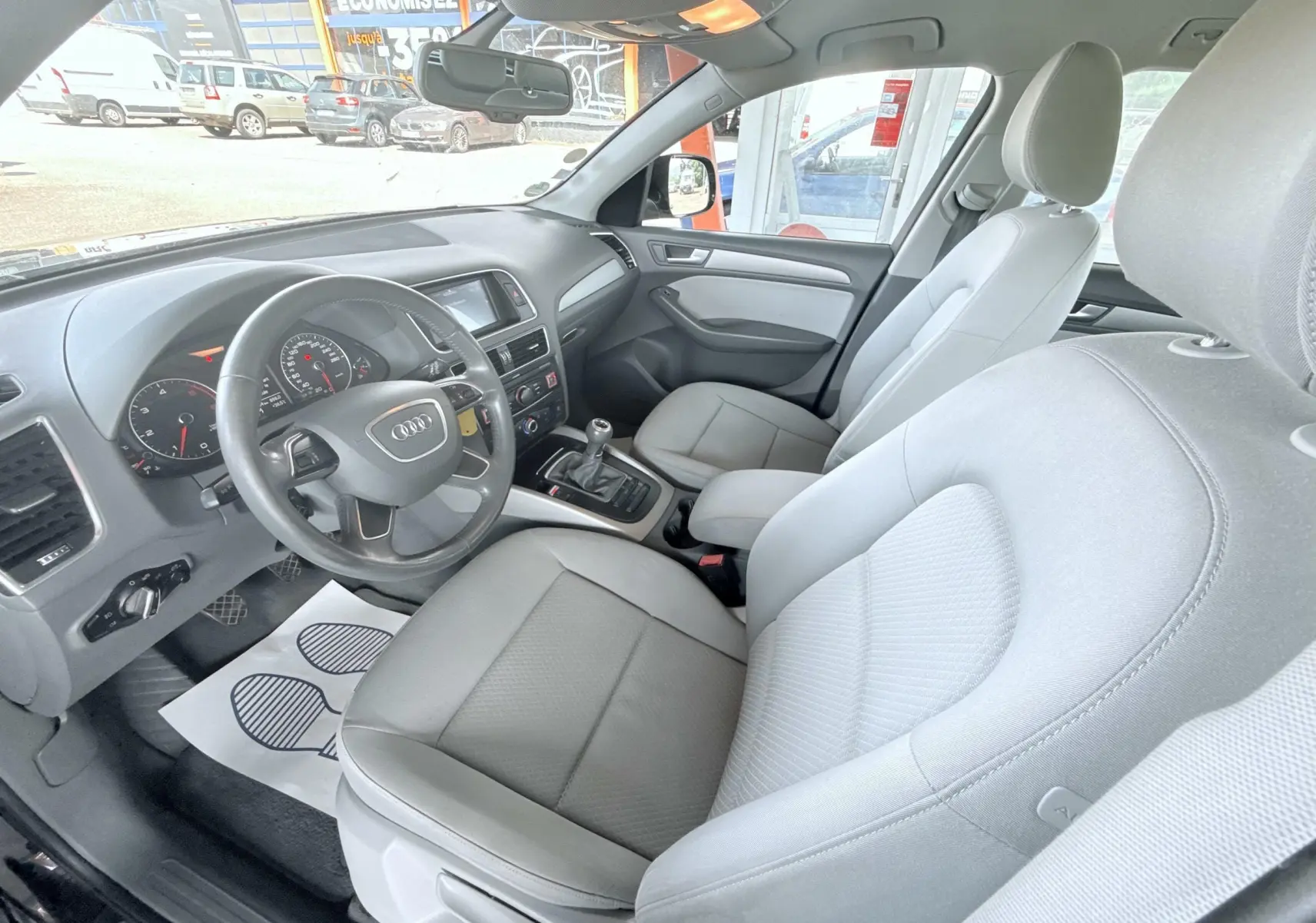 Vue intérieure côté conducteur de l'Audi Q5 2014 noir, montrant le volant, la boîte manuelle et les sièges gris clair.