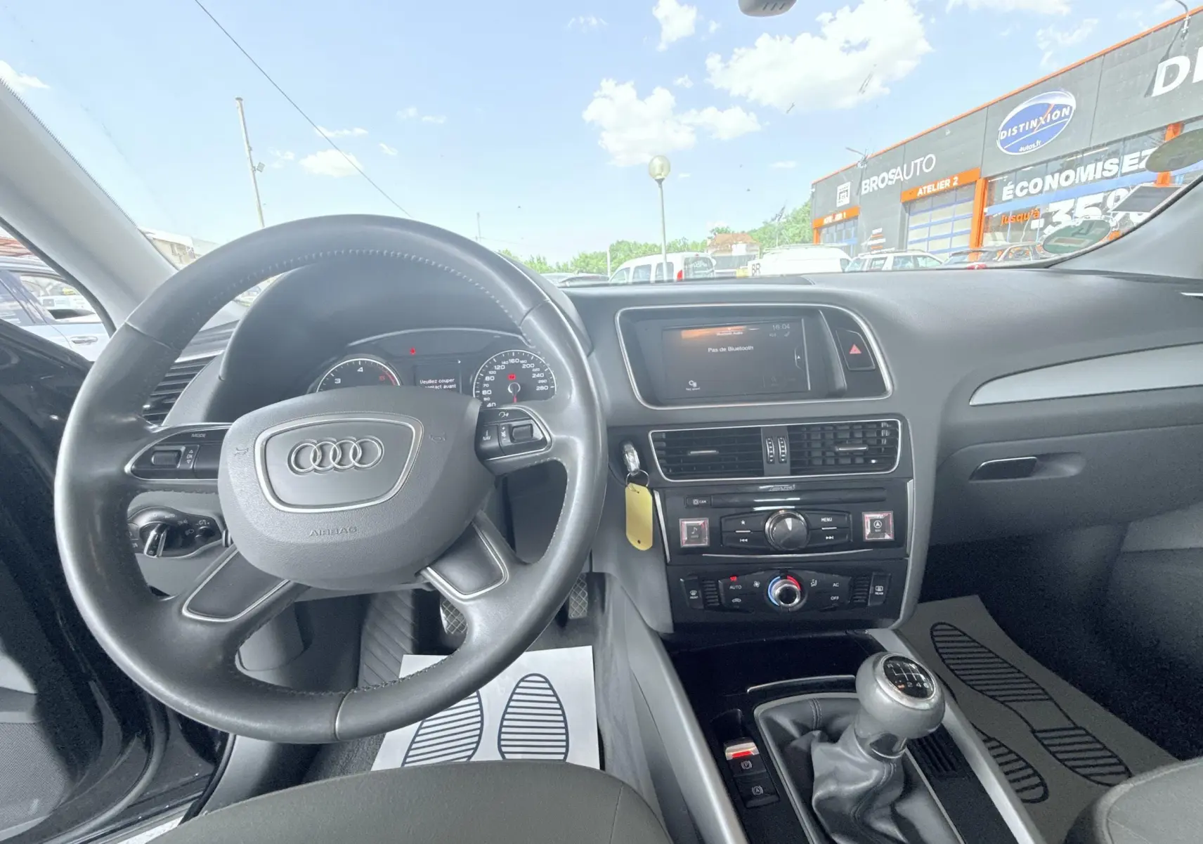 Vue intérieure de l'Audi Q5 2.0 TDI 150ch Business noir de 2014, montrant le volant, tableau de bord et levier de vitesses manuel.