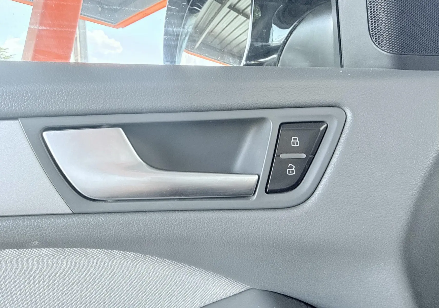 Poignée intérieure de porte côté gauche de l'Audi Q5 noire, avec boutons de verrouillage visibles.