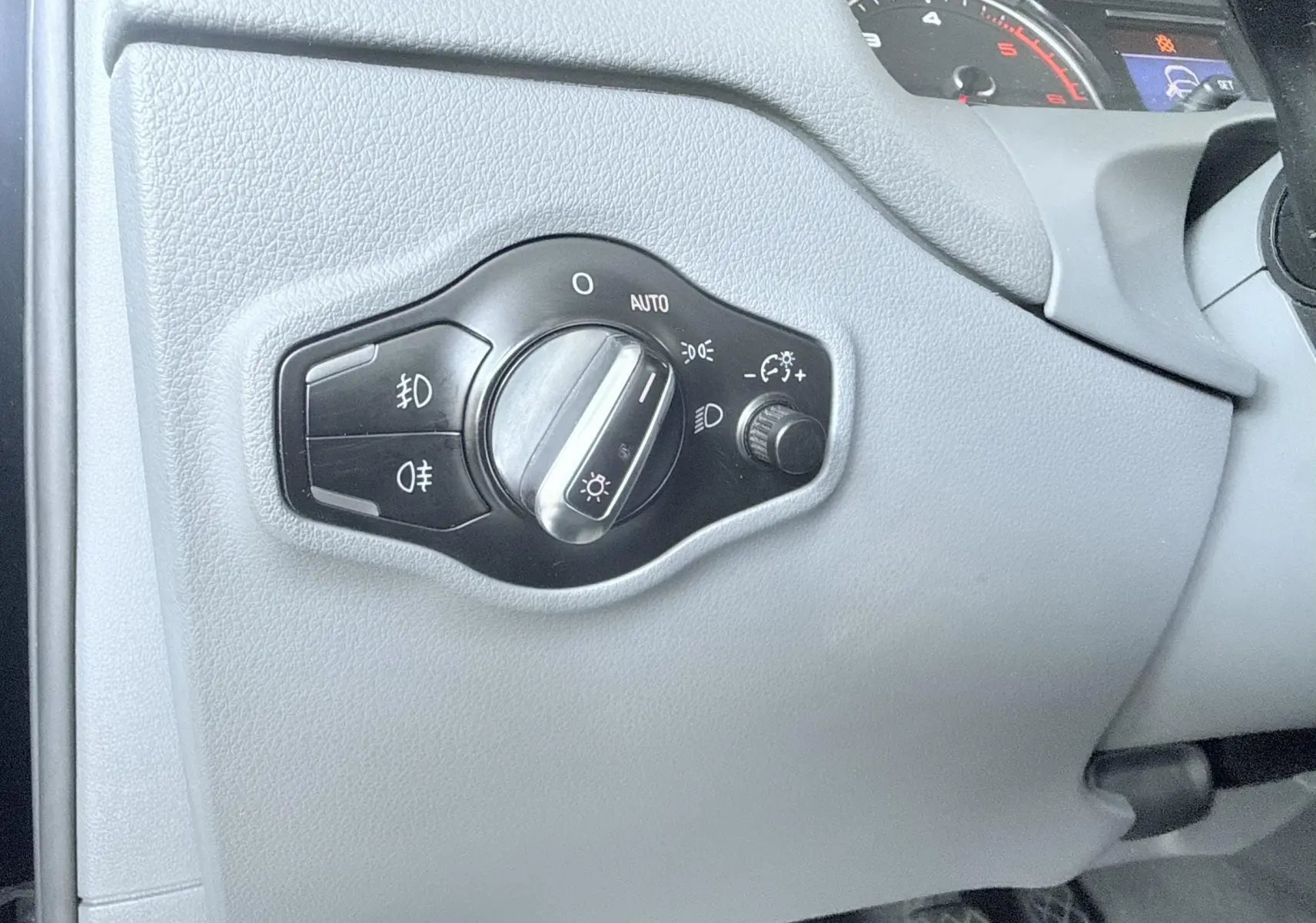 Gros plan sur le bouton de commande des phares à gauche du tableau de bord de l'Audi Q5 2014 noir.