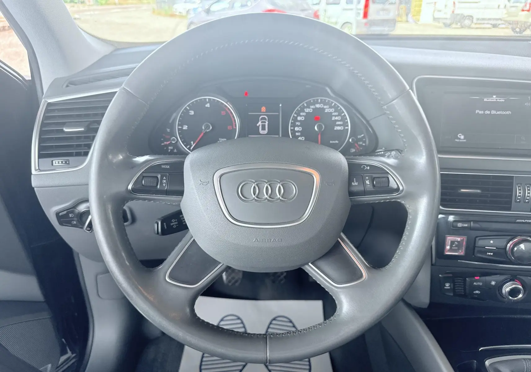 Vue intérieure centrée sur le volant noir d'un Audi Q5 2014, avec tableau de bord et console centrale visibles.