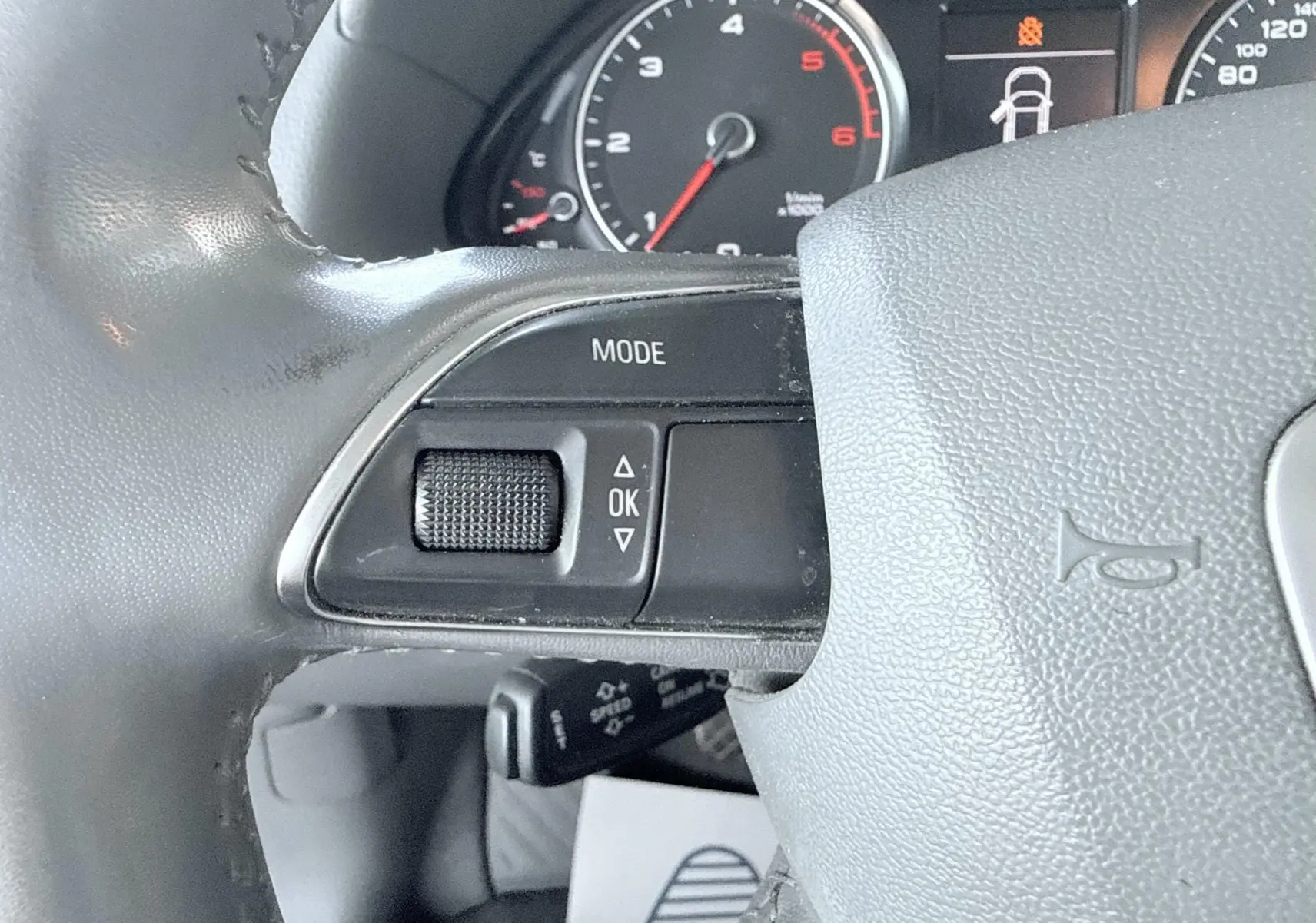 Gros plan sur le volant noir de l'Audi Q5 2014, montrant les commandes de mode et le compteur partiel en arrière-plan.