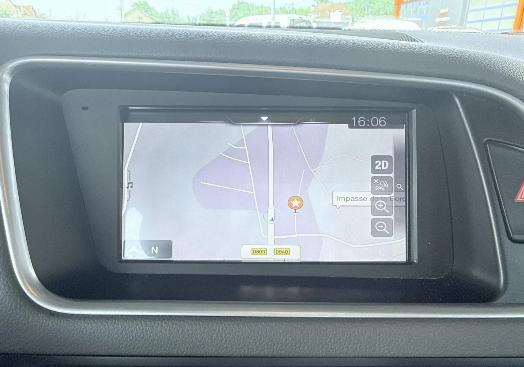 Écran de navigation central de l'Audi Q5 2014 affichant une carte en mode 2D, entouré de tableau de bord noir.