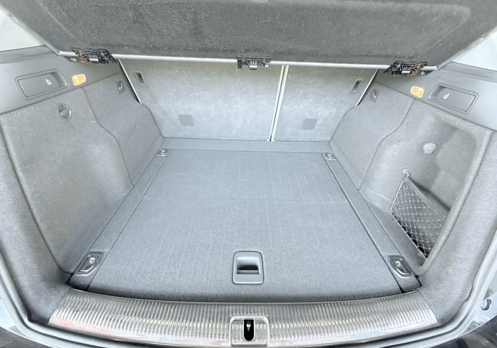 Coffre ouvert vu de l'arrière d'un Audi Q5 noir, montrant un espace de chargement propre et bien agencé.