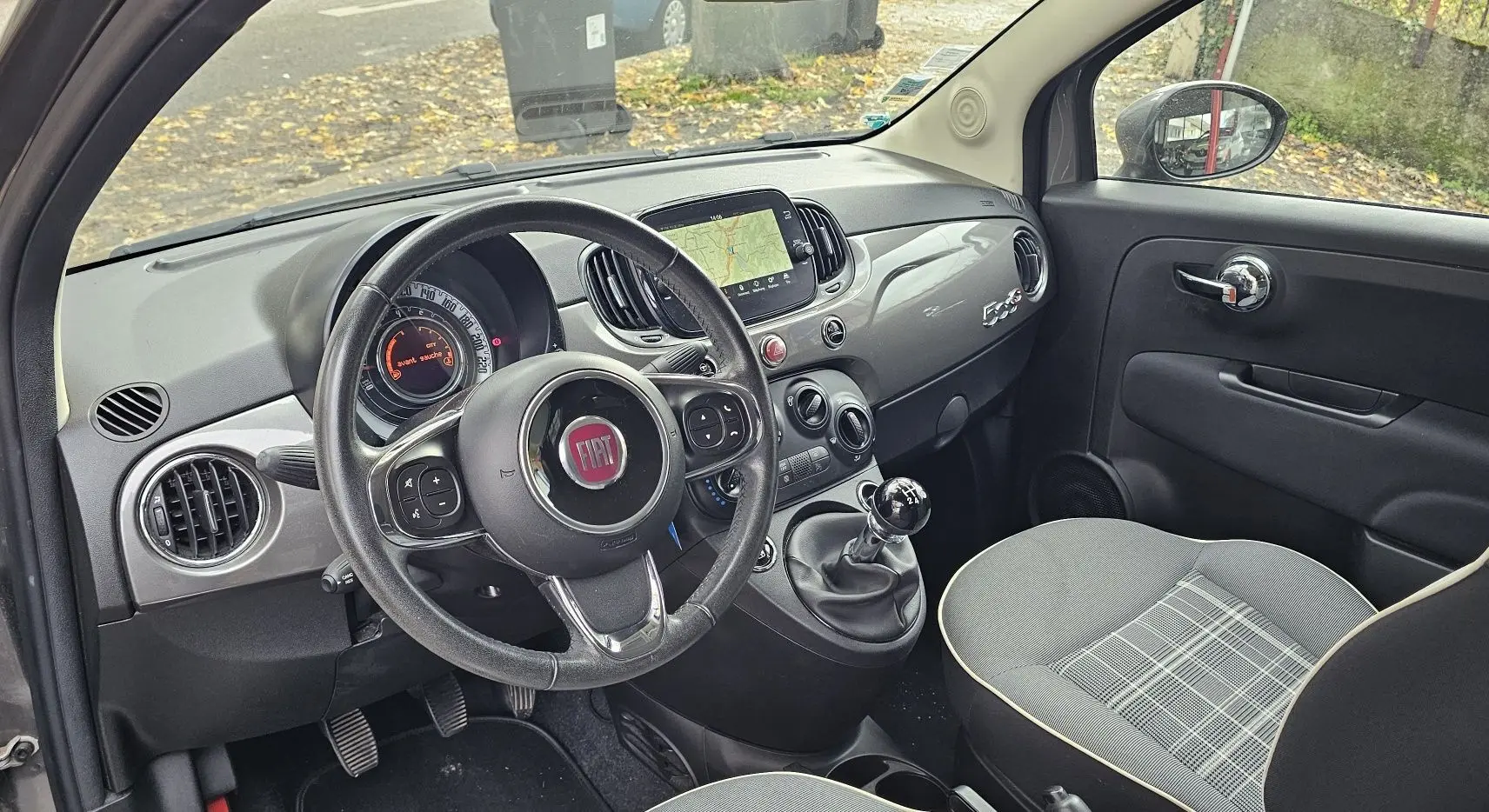 Fiat 500C grise électroclash vue 3/4 arrière côté droit avec toit rouge cabriolet fermé sur parking.