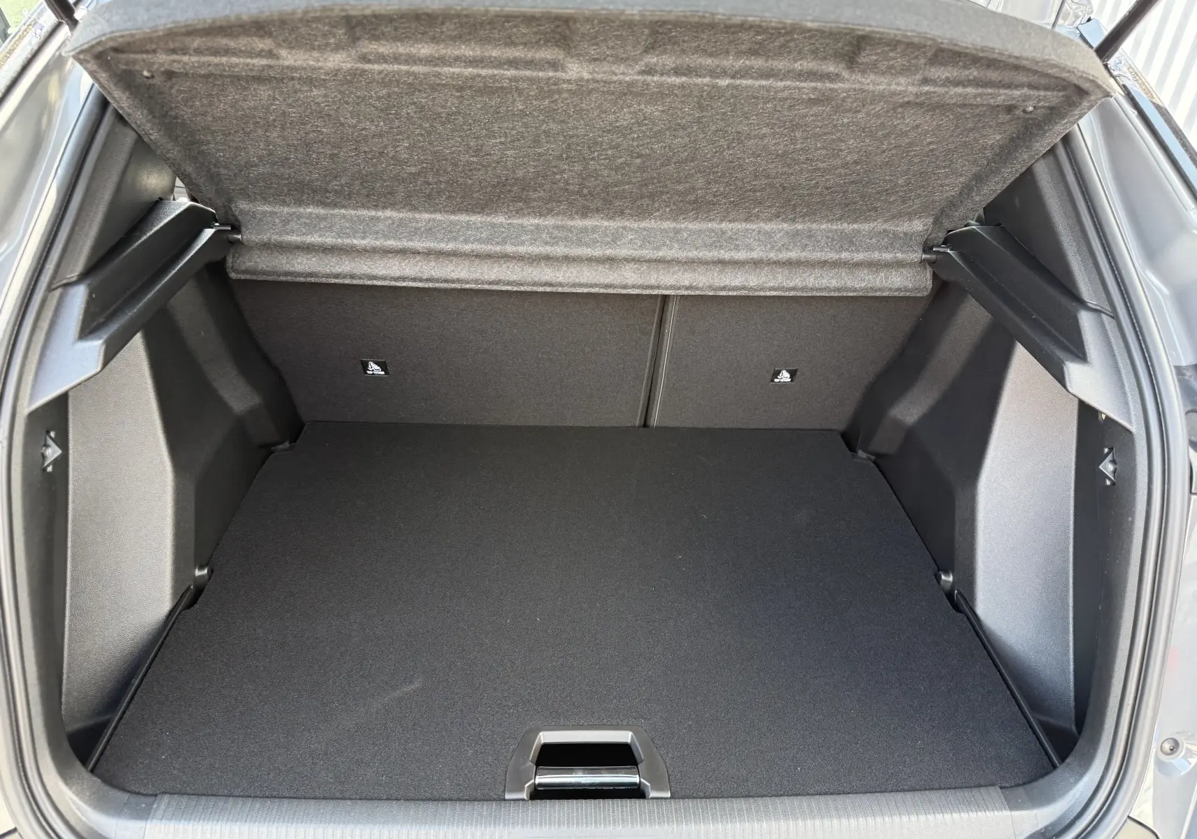 Coffre ouvert vu de l'arrière du Peugeot 2008 gris selenium, montrant un espace de chargement propre et spacieux.