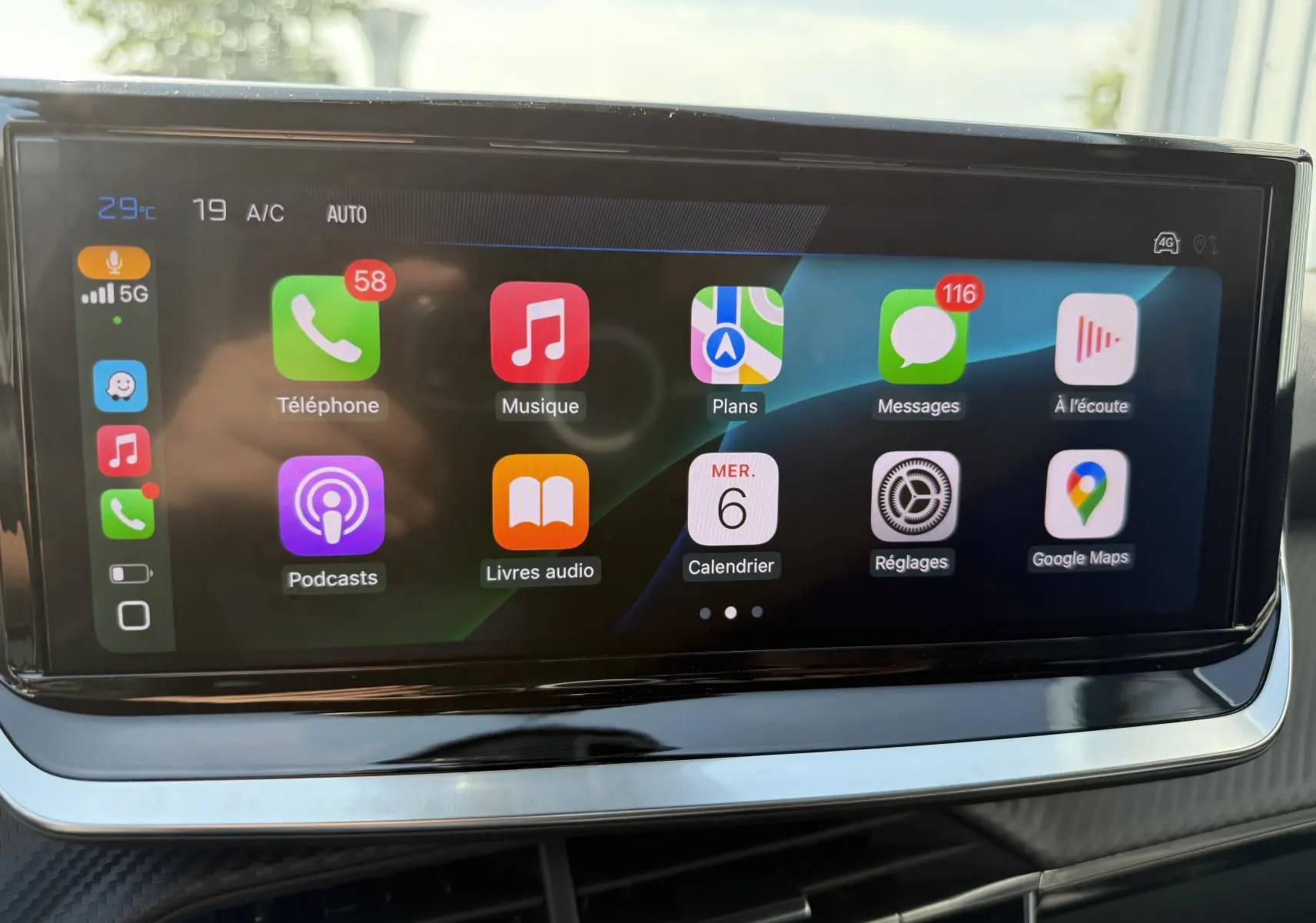 Écran tactile central du Peugeot 2008 Hybrid 145ch Allure 2025 affichant les applications Apple CarPlay en intérieur noir brillant.