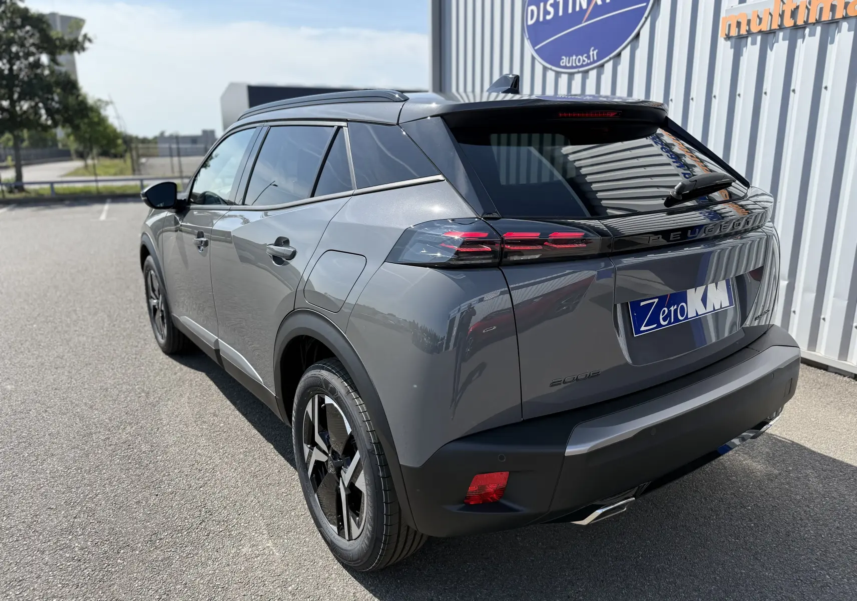 Vue 3/4 arrière droite d'un Peugeot 2008 gris selenium hybride, avec feux arrière LED et jantes noires bicolores.