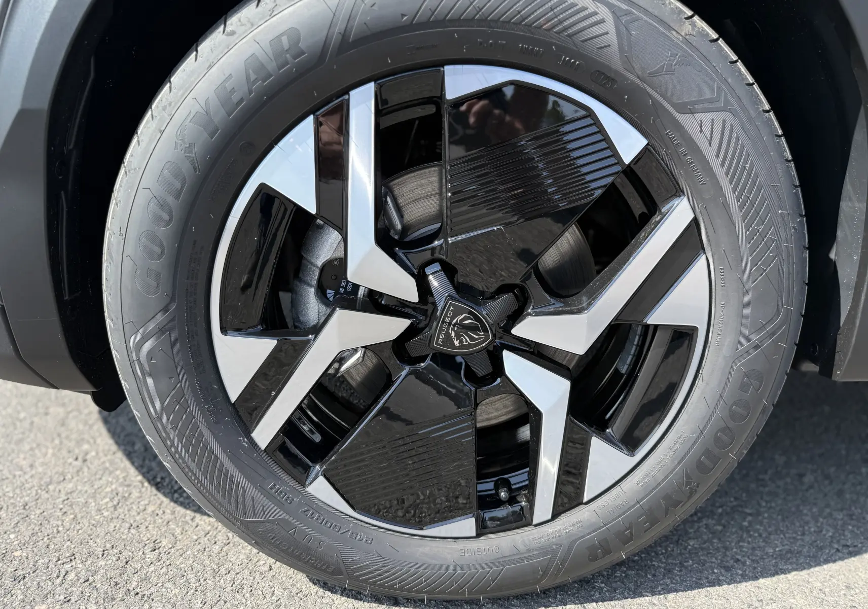 Gros plan sur la jante avant droite du Peugeot 2008 gris Selenium, avec un design bicolore noir et argent distinctif.