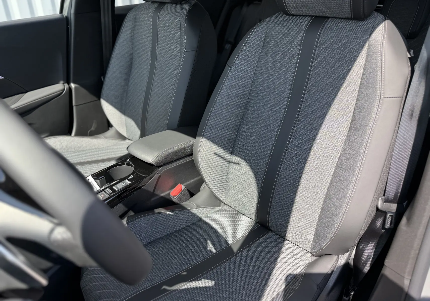 Vue rapprochée des sièges avant en tissu gris et cuir noir du Peugeot 2008 Hybrid 145ch Allure 2025, côté conducteur.
