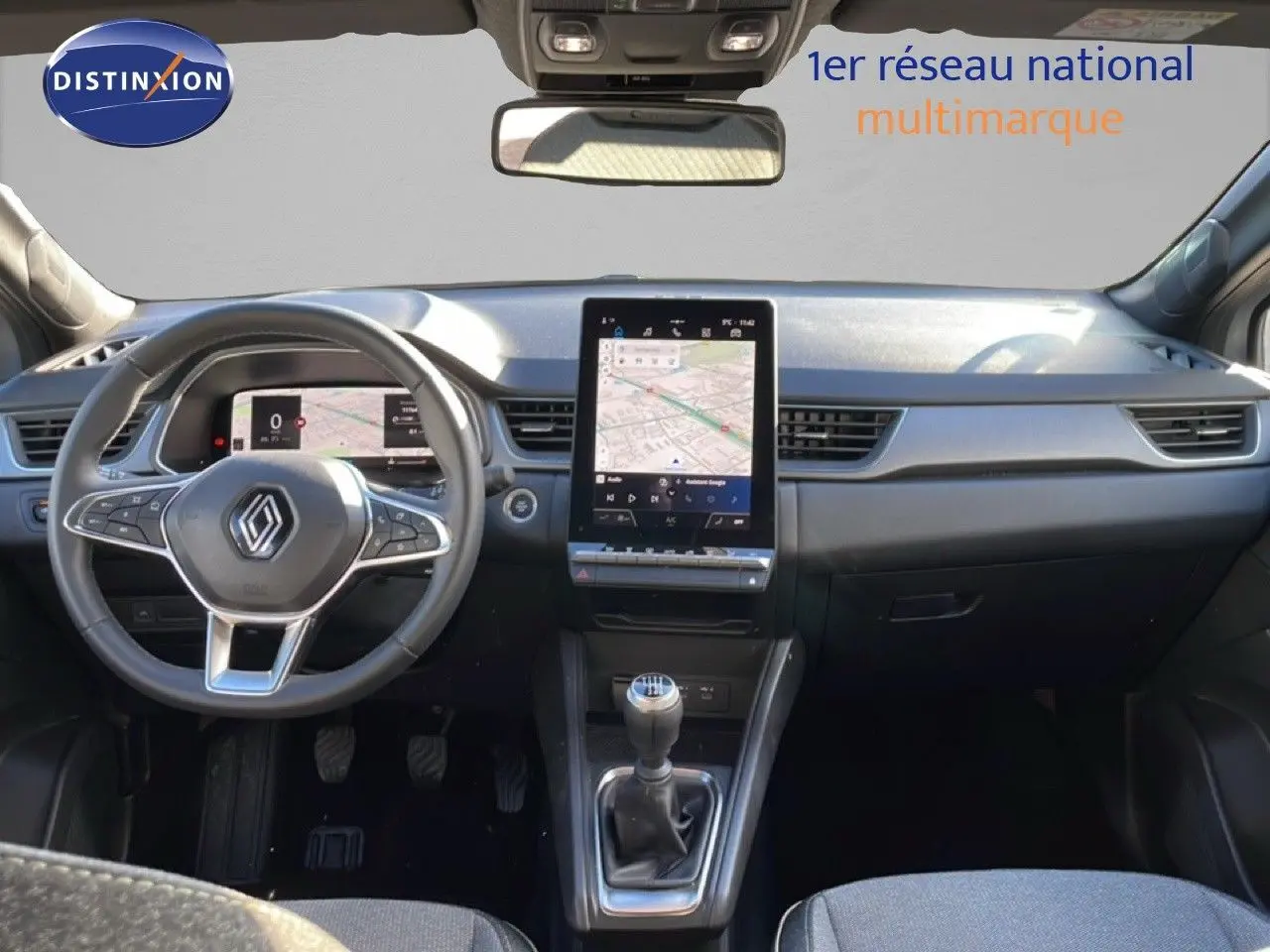 Vue intérieure avant du Renault Captur 2025, tableau de bord gris avec écran tactile vertical et levier de vitesses manuel.