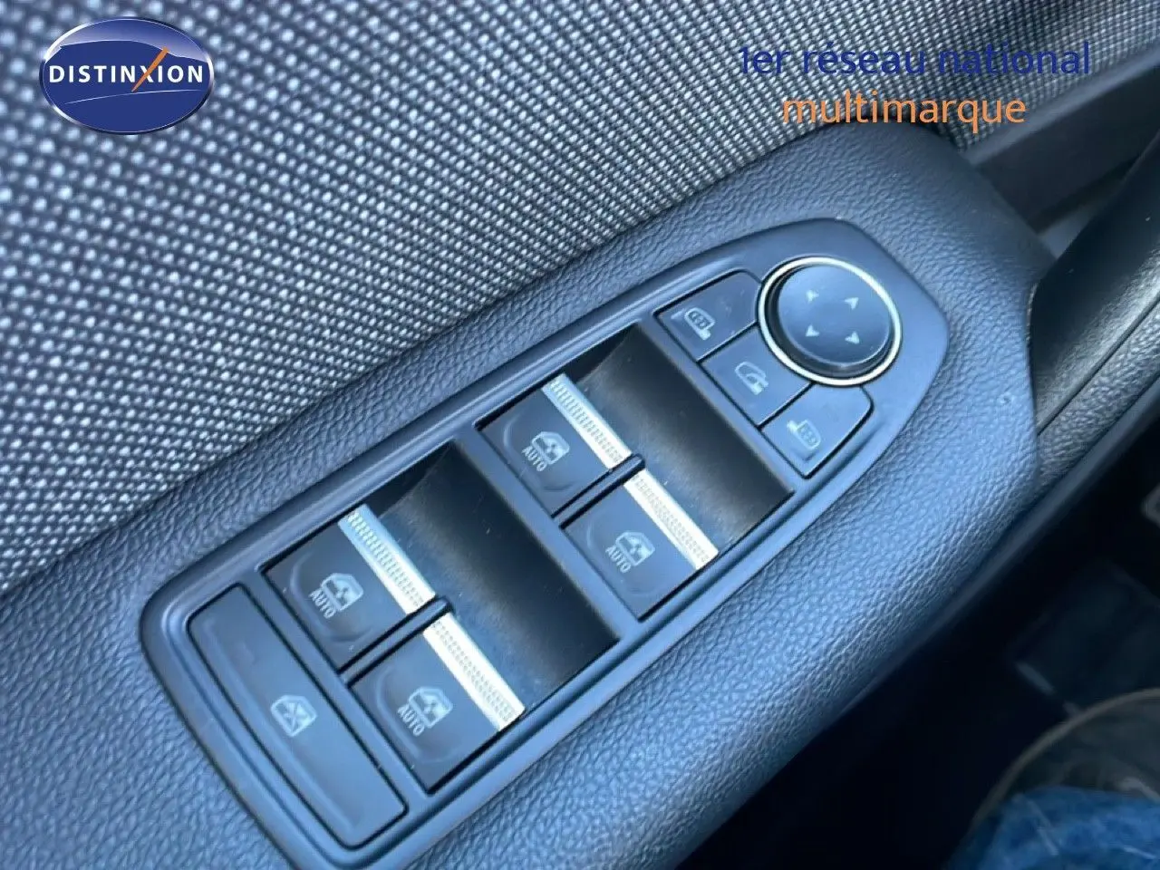 Gros plan sur les commandes de lève-vitres côté conducteur d’un Renault Captur gris Rafale métal avec toit noir.