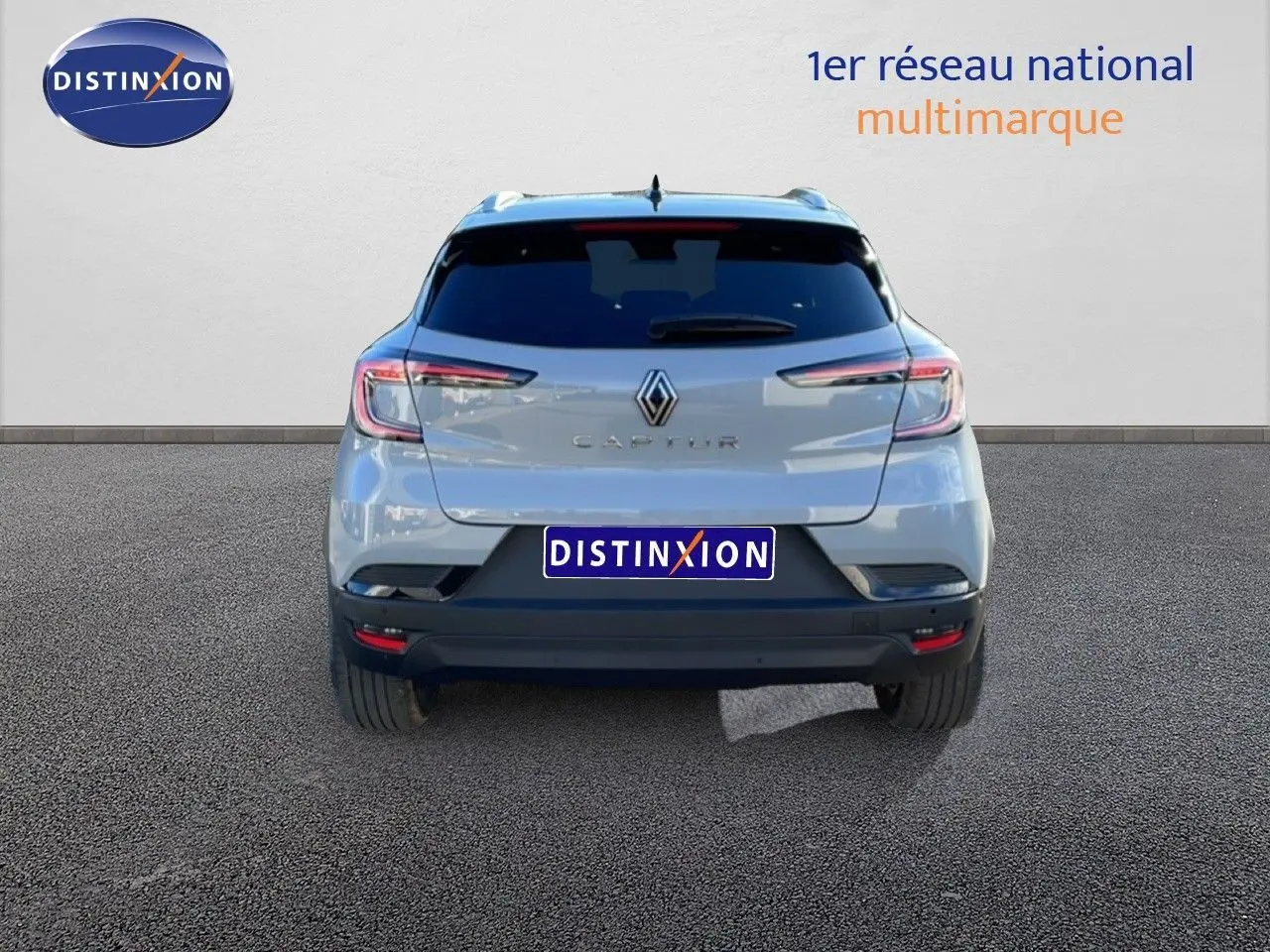 Vue arrière d'un Renault Captur gris Rafale métallisé avec toit noir, sur fond neutre avec logo Distinxion.