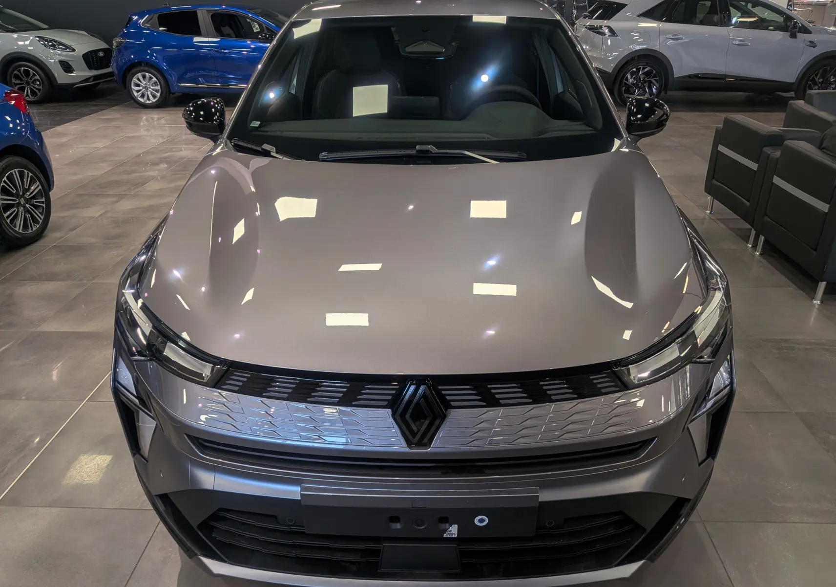 Vue avant rapprochée de la Renault SYMBIOZ E-TECH gris Cassiopé, mettant en valeur sa calandre moderne et ses phares fins.