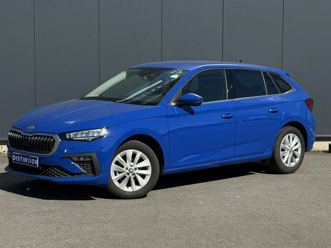 Skoda Scala bleu Energy en 3/4 avant droit, vitres surteintées et jantes alliage 16 pouces visibles.