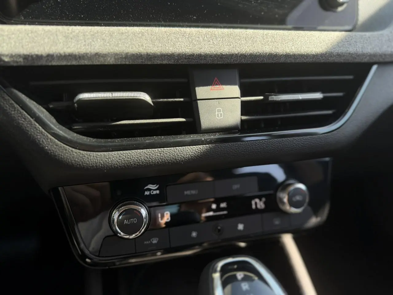 Gros plan sur la console centrale noire brillante de la Skoda Scala TSI 116 DSG7 avec commandes climatisation automatique.