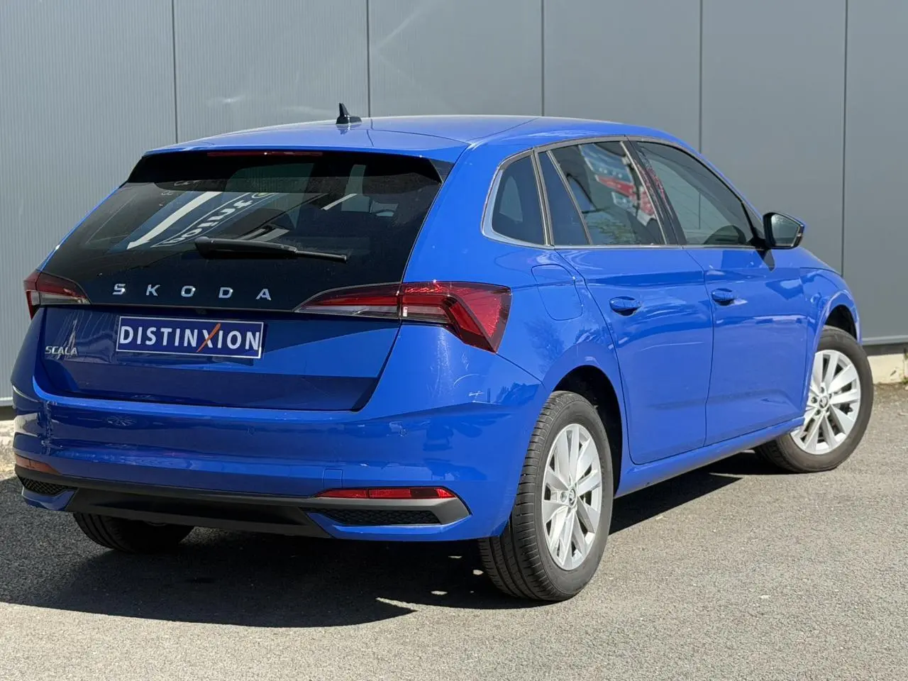 Vue 3/4 arrière droite d'une Skoda Scala TSI 116 DSG7 bleu Energy avec vitres surteintées et jantes alliage 16 pouces.