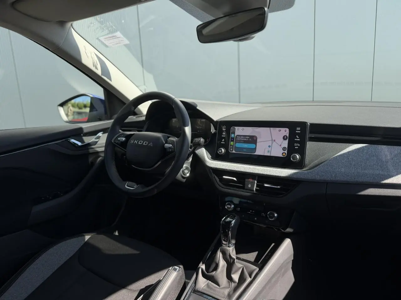 Vue intérieure côté conducteur de la Skoda Scala bleu Energy, avec tableau de bord moderne et écran tactile central allumé.