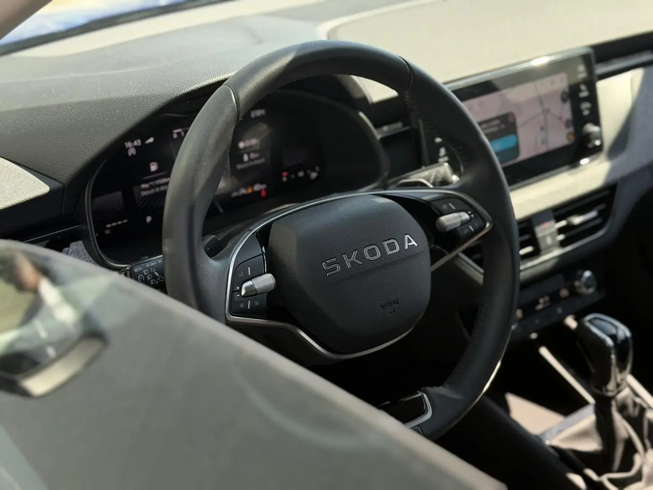 Vue rapprochée du volant en cuir noir marqué SKODA et du tableau de bord numérique de la Skoda Scala 2025.