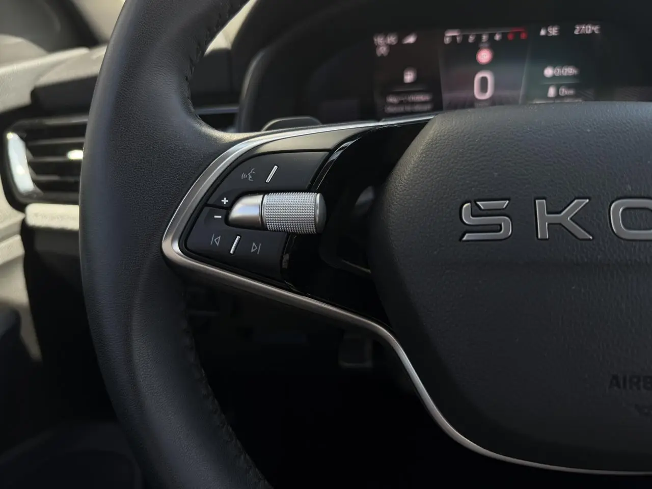 Gros plan sur le volant cuir noir de la Skoda Scala 2025 avec commandes multifonctions et tableau de bord numérique flou.