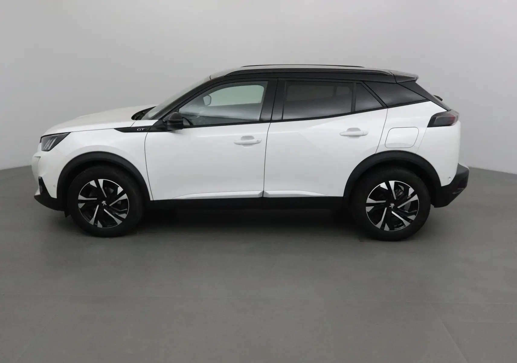 Peugeot 2008 GT blanc nacré avec toit noir, vue de profil côté gauche, jantes alliage noires distinctives.