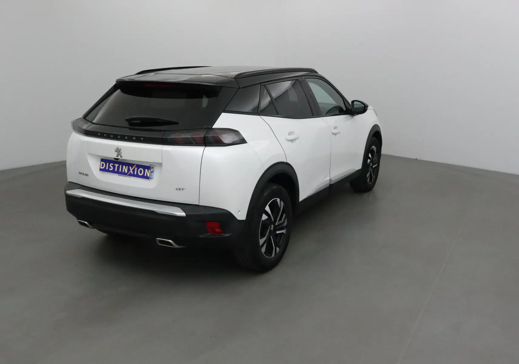 Peugeot 2008 GT blanc nacré avec toit noir, vue 3/4 arrière côté droit dans un studio neutre.