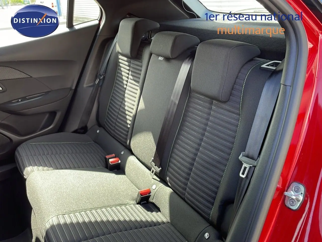 Vue intérieure arrière montrant les sièges noirs avec surpiqûres vertes du Peugeot 2008 rouge Elixir 2025.