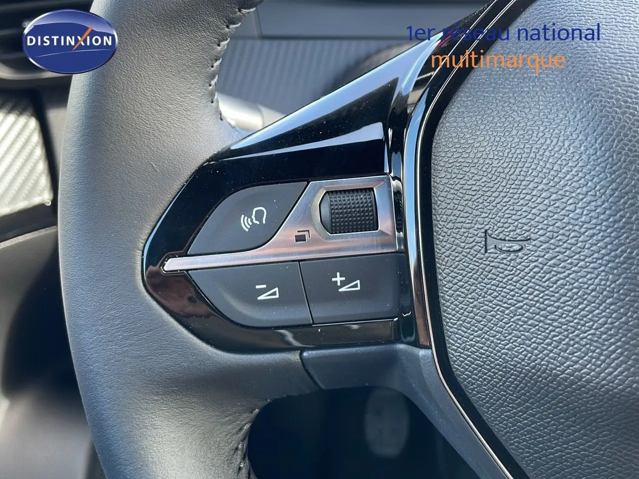 Gros plan sur les commandes gauche du volant du Peugeot 2008 rouge Elixir Metal, mettant en valeur les boutons de réglage audio.