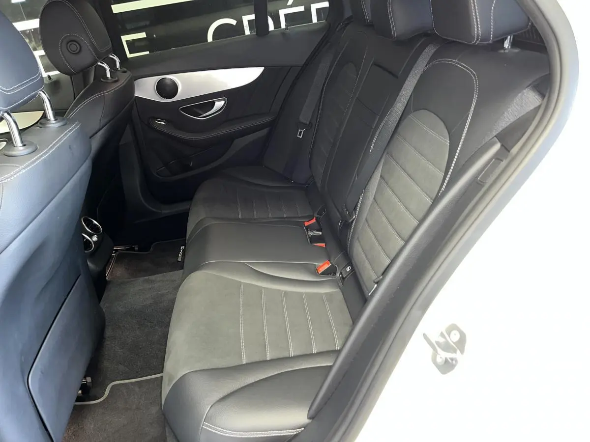 Vue côté droit de l'habitacle arrière du break Mercedes Classe C blanc, sièges en cuir noir et alcantara avec surpiqûres grises.
