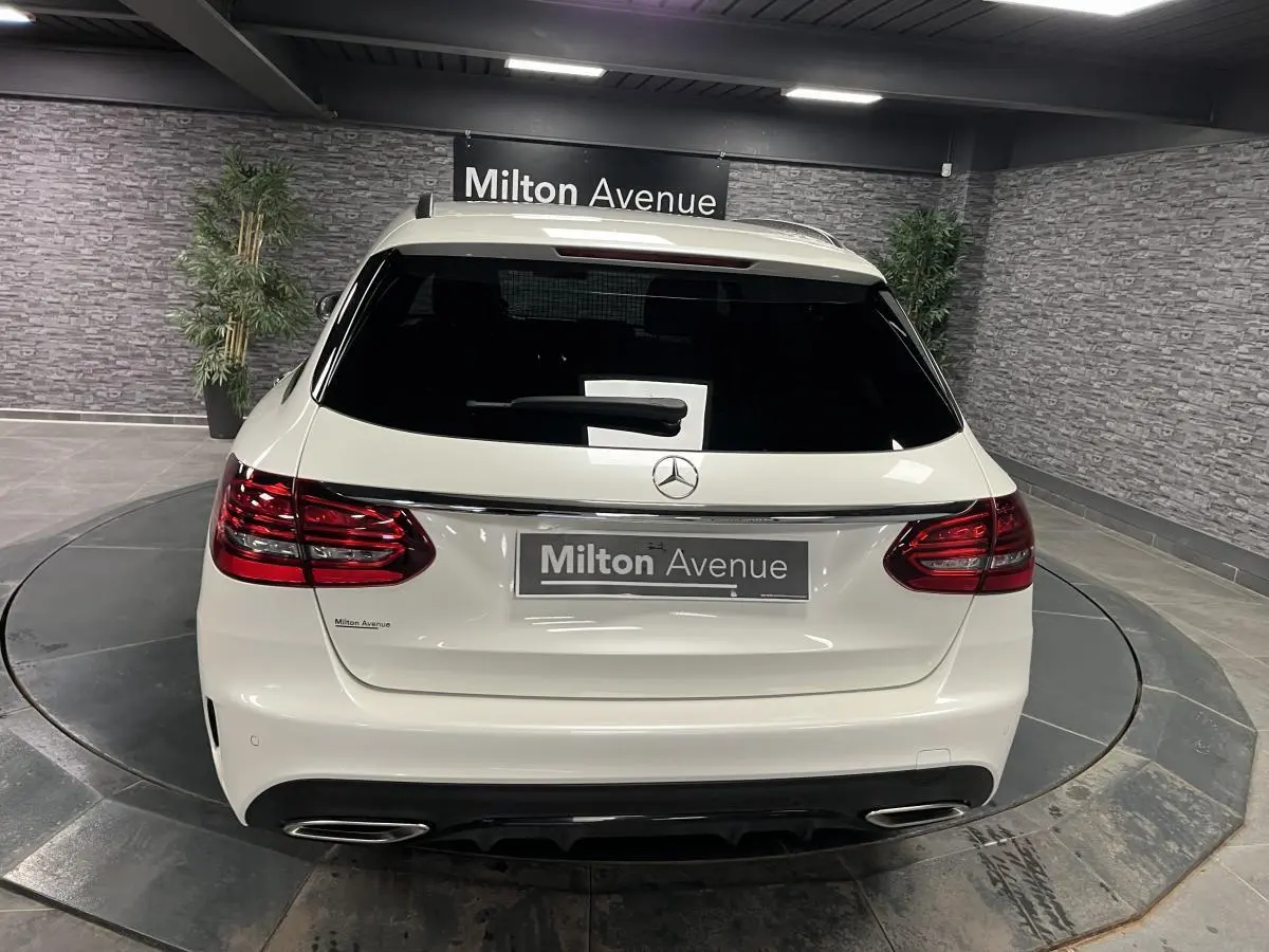 Vue arrière d'un break Mercedes Classe C blanc avec feux LED et double sortie d'échappement chromée dans un showroom.