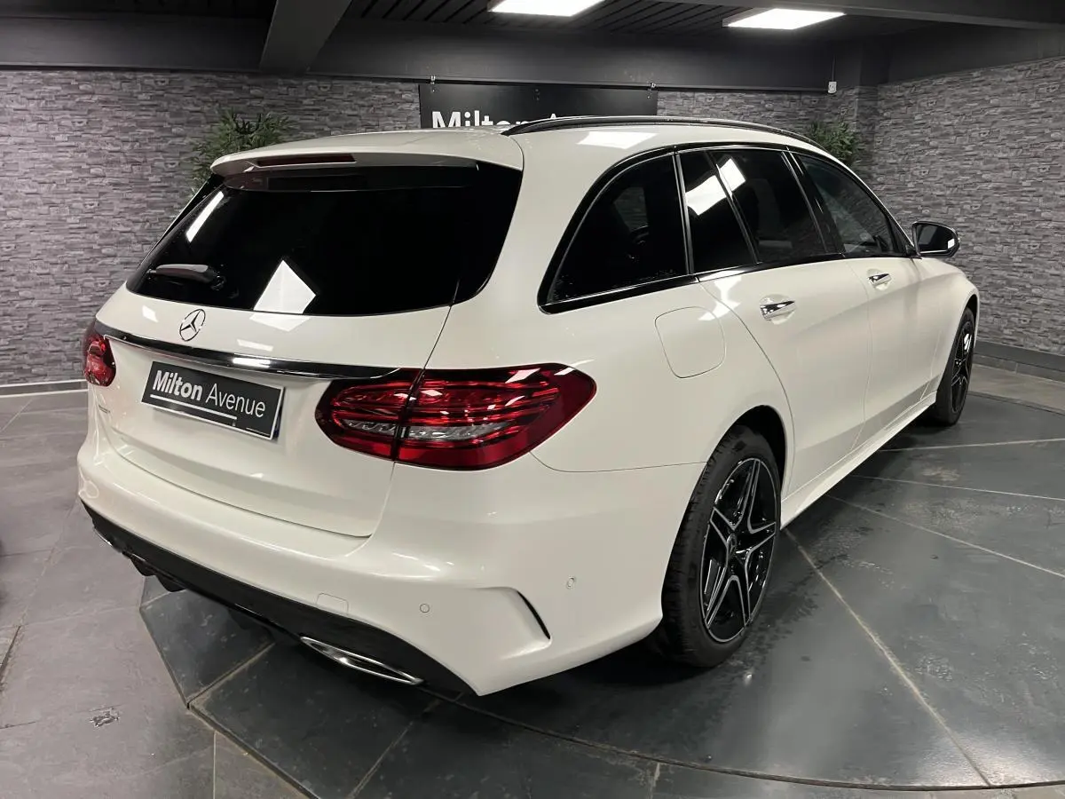 Mercedes Classe C Break blanc en 3/4 arrière droit avec jantes AMG noires et vitres teintées.