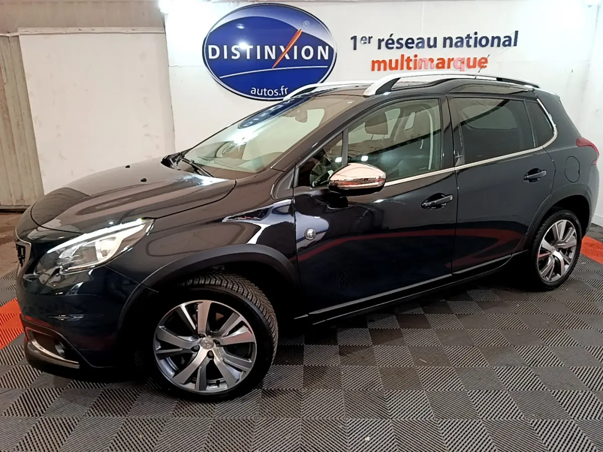 Peugeot 2008 gris foncé vue de profil côté gauche avec jantes alliage et barres de toit chromées.