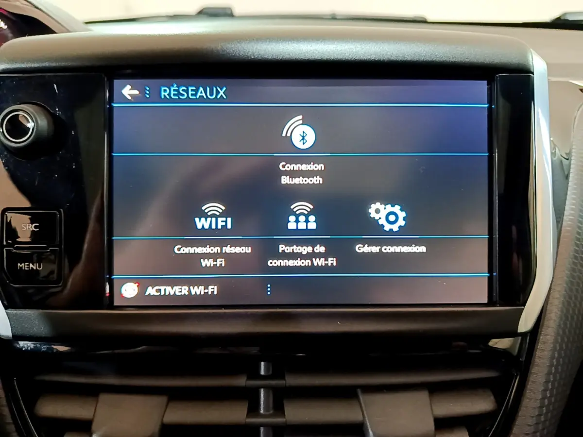 Écran tactile central affichant les options réseau Bluetooth et Wi-Fi dans l'habitacle d'un Peugeot 2008 gris foncé.