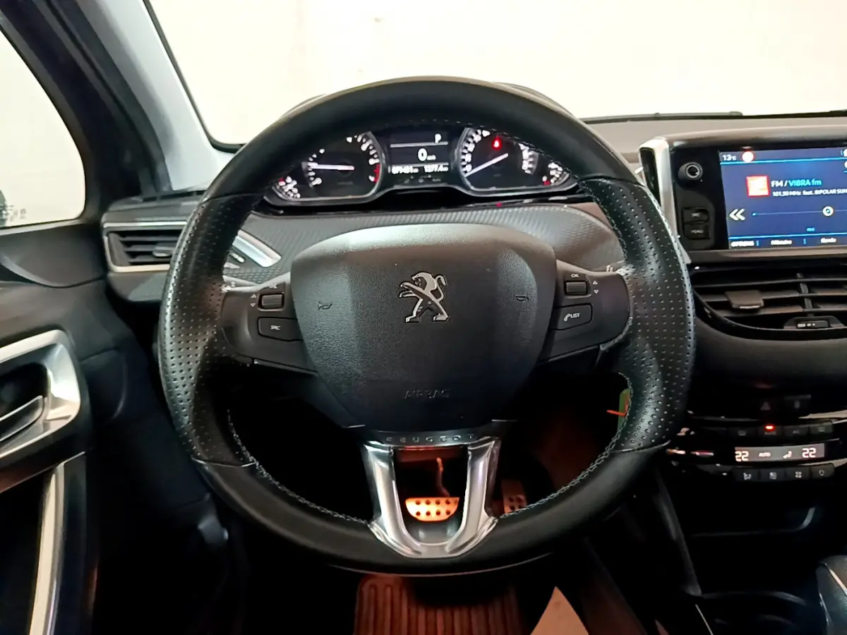 Vue intérieure centrée sur le volant cuir noir et le tableau de bord numérique du Peugeot 2008 gris foncé de 2019.