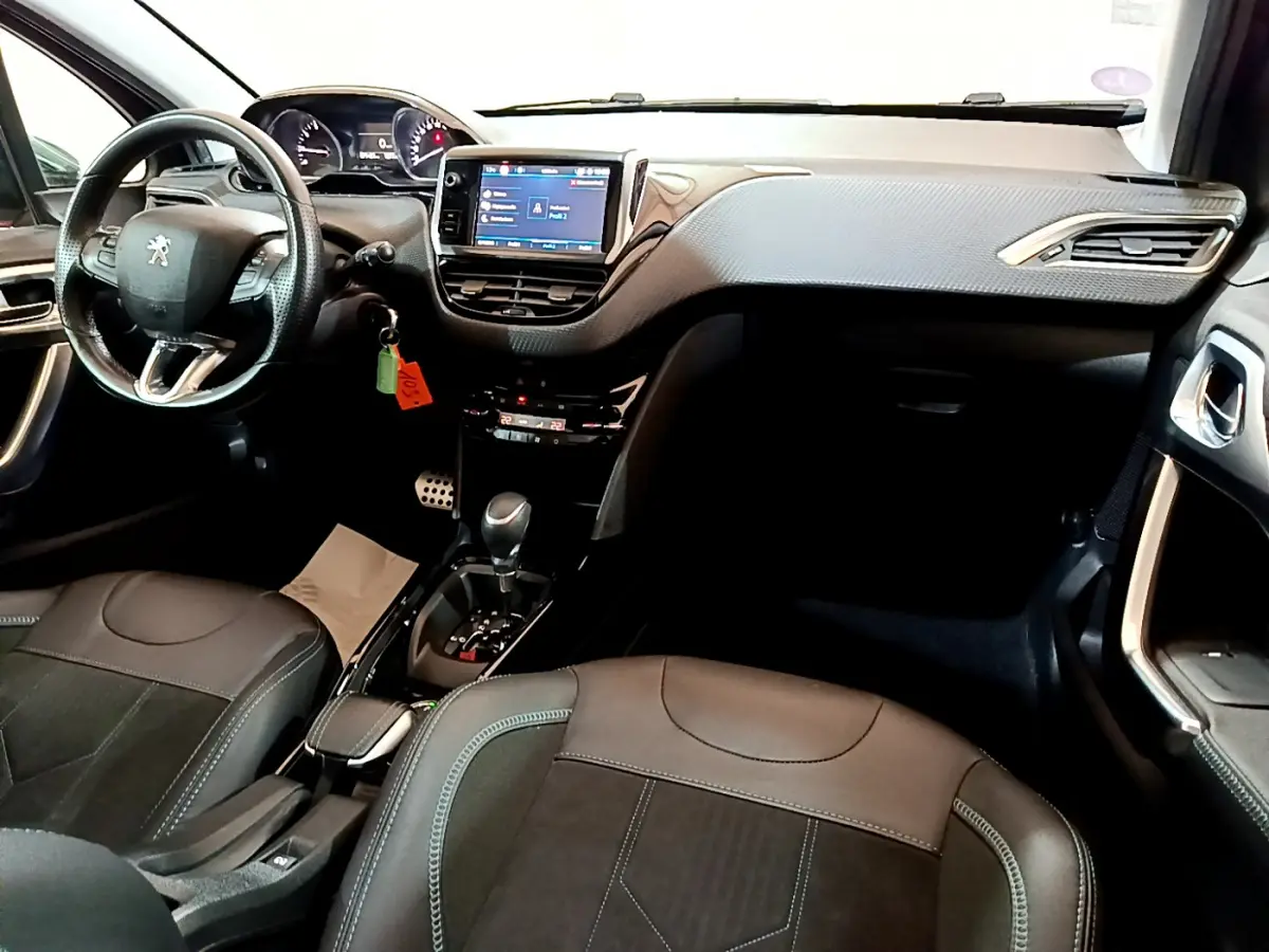 Intérieur du Peugeot 2008 gris foncé, vue de face montrant le tableau de bord avec écran tactile et volant cuir multifonctions.