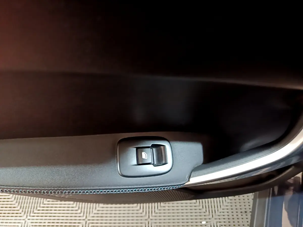 Bouton de commande de vitre électrique sur la porte côté gauche d'un Peugeot 2008 gris foncé, version Crossway.