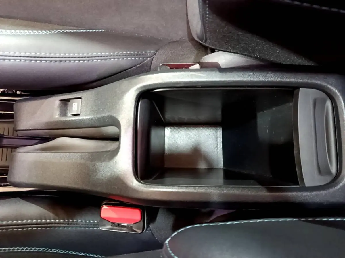 Vue plongeante sur le rangement central noir entre les sièges avant du Peugeot 2008 gris foncé de 2019.