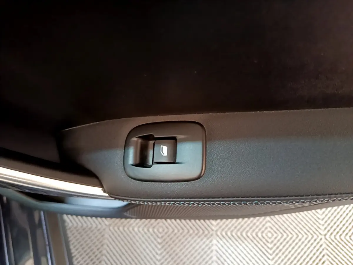 Bouton de commande de vitre électrique sur la porte intérieure d'une Peugeot 2008 gris foncé, vue rapprochée.