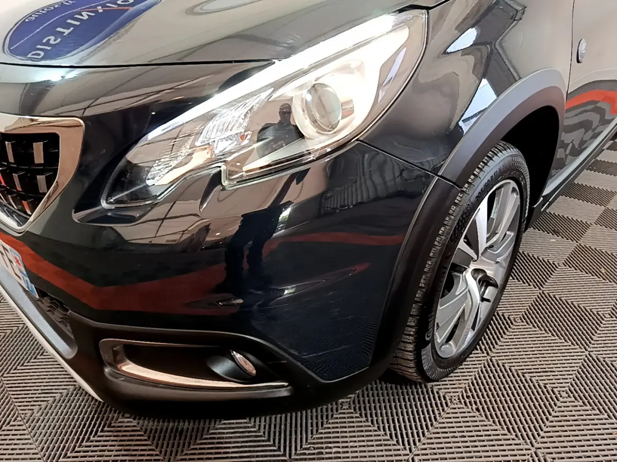 Gros plan sur l'avant droit gris foncé du Peugeot 2008 2019 avec phare et jante alliage visible.